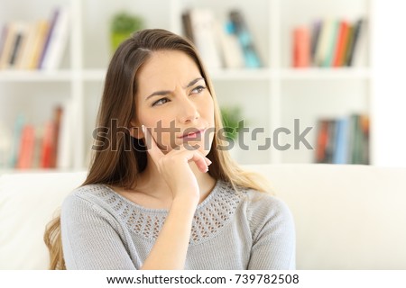 Front view portrait of a woman wondering sitting on a sofa at home