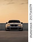 Front view of a powerful car at the parking lot with sunset background