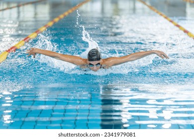 Front view of a powerful elite female swimmer competitor performing butterfly swim technique, arm stroke movements. Swim fly and dolphin kick concept. - Powered by Shutterstock