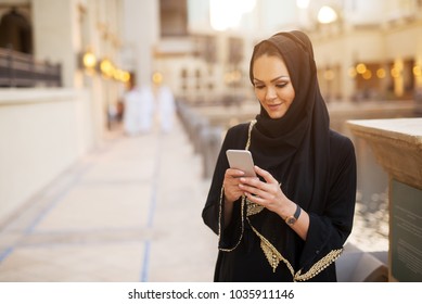 Front View Of A Pretty Young Girl Smiling While Looking At Her Phone.