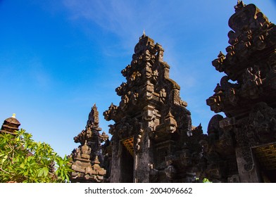 The Front View Of Pura Goa Lawah Or Bat Cave Temple In Tulamben, Bali, Indonesia Showing Balinese Art On Gapura Or Gate Structure On Blue Sky