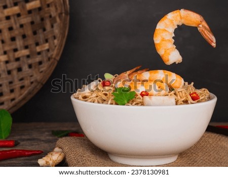 Front view of ramen instant noodle soup with shrimp in white bowl on wooden table background. Asia Food, Tom Yum Kung