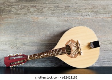 Front view of a reclined wooden flatback mandolin on a black table with a weathered wood background