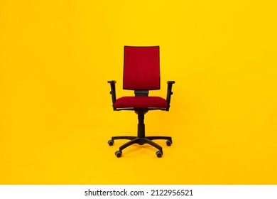 Front View Of Red Adjustable Office Chair Over Yellow Background In Studio. Comfortable Ergonomic Furniture For Workplace Concept. Full Length Shot, No People