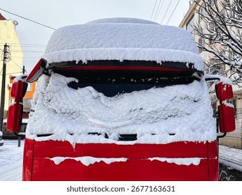 Front View of a Red Bus Completely Covered in a Thick Layer of Snow