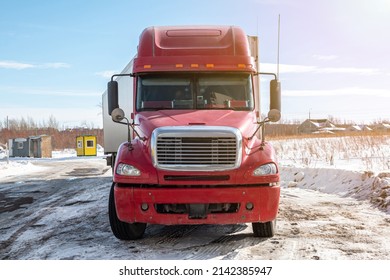 Front view of the red long-distance bonnet truck with a white semitrailer in the countryside at winter