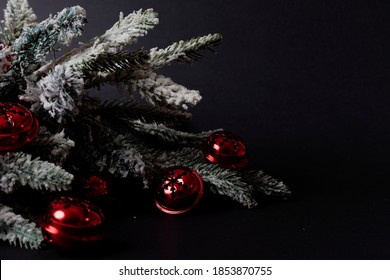 Front View Of Red Sleigh Bells In Front Of A Christmas Tree With Snow On Black Dark Background