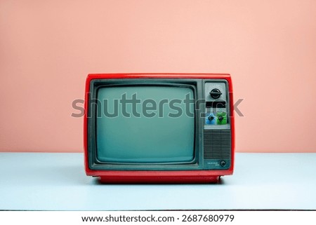 Front view, retro red old television with blank screen on blue floor, vintage analog TV with pink wall background.