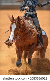The front view of a rider sliding the horse in the sand.