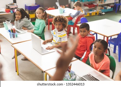 Vue d'avant d'une rangée d'élèves écoutant leur professeur en classe à l'école tandis qu'un de leurs camarades de classe ne dessine que sur une table