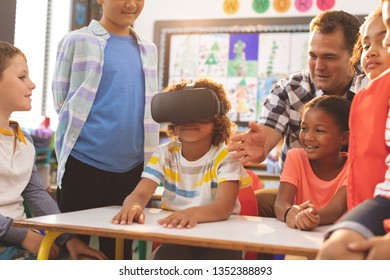 Front view of a schoolboy using virtual reality headset with his classmate and teacher at school - Powered by Shutterstock - Get 15% off with code: PIKWIZARD15