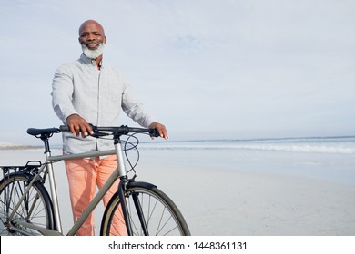 Front view of senior African-American walking with bicycle on beach on beautiful day. Authentic Senior Retired Life Concept - Powered by Shutterstock