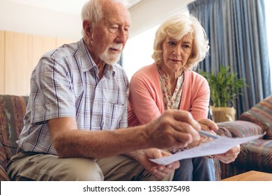 Front view of senior Caucasian couple looking at bill while sitting in retirement home - Powered by Shutterstock