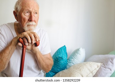 Front view of senior Caucasian male patient sitting upset on bed with cane at retirement home, Social distancing and self isolation in quarantine lockdown for Coronavirus  - Powered by Shutterstock