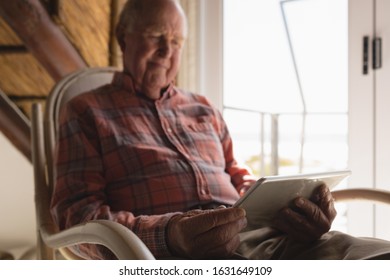 Front view of a senior man using laptop on a rocking chair in living room at home - Powered by Shutterstock