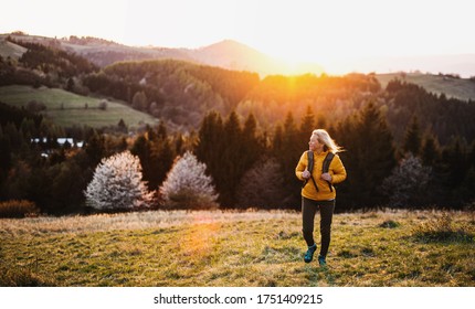 Front view of senior woman hiker walking outdoors in nature at sunset. - Powered by Shutterstock