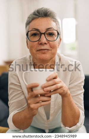 Front view of a senior woman holding a cup.