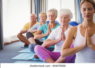 Front view of seniors relaxing with fitness instructor in retirement house
