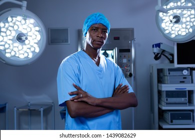 Front View Of Serious African-american Male Surgeon With Arms Crossed Standing In Operating Room Of The Hospital