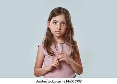 Front View Of Serious Little Girl Touching Her Hair And Looking At Camera. Beautiful Caucasian Female Child Wearing Pink T-shirt. Childhood Concept. Isolated On White Background In Studio. Copy Space