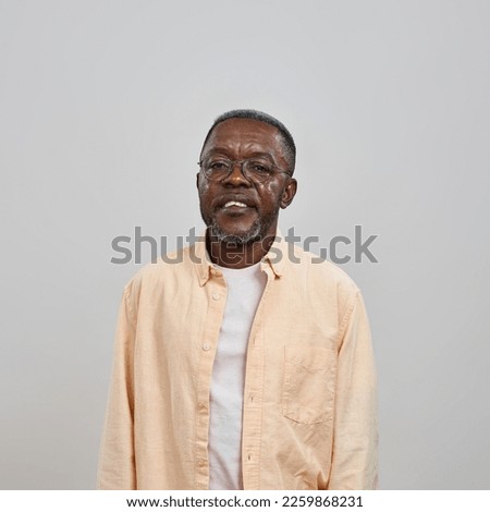 Front view of serious senior black man looking at camera. Male person wearing glasses and casual clothes. Concept of modern elderly lifestyle. Isolated on white background. Studio shoot. Copy space