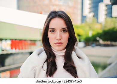 Front view of serious young woman looking at camera. Close up portrait of brunette teenage girl standing outdoors. Photo of isolated pretty female lady with sad expression. High quality photo - Powered by Shutterstock