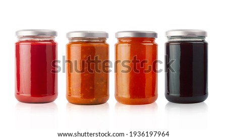 front view of set of small jam and vegetable jars in different colors without labels and shiny metallic lid covers isolated on white background