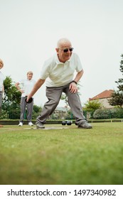 A front view shot of a senior man taking his shot in a game of lawn bowling.