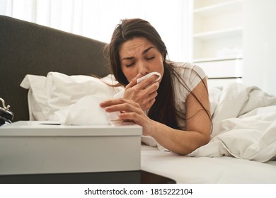 Front View Of A Sick Dark-haired Female Reaching For A Tissue Box On The Bedside Table