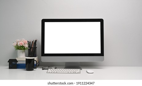 Front view of simple workspace with modern computer and office supplies. Blank screen for your text or advertising content.