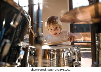 Front view of small boy indoors at home, playing drums.