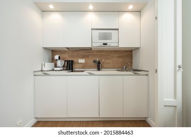 Front View Of Small Kitchen In White And Oak Wood Tones, Microwave And Accessories Included In A Holiday Rental Apartment