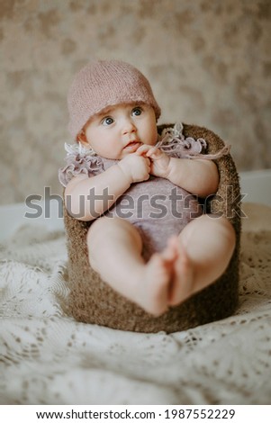 Front view of small toddler sitting at the chair. Concept of baby photoshoot.