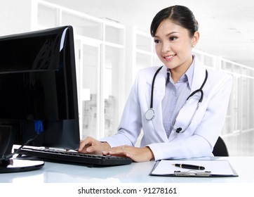 Front View Of Smiling Woman Doctor Working On Computer