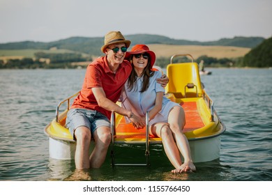 Front view of smiling young couple sitting on pedal boat. Portrait of man and woman in love enjoying boating on the lake.