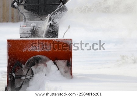 front view of a snowblower in action after a storm with snow churning in impeller blade. winter season weather background design element.