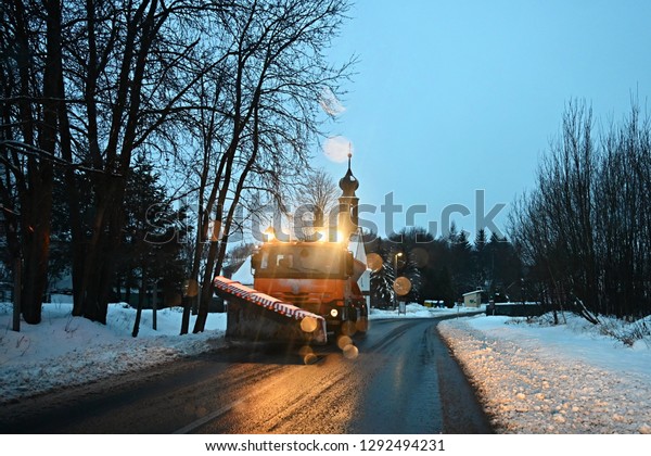 Front view of snowplow service truck - gritter\
car spreading salt on the road. Maintenance of roads in winter in\
the mountains.