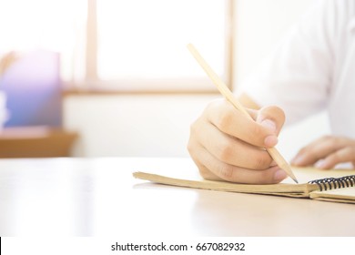 Front View Soft Focus.university Or High School Student Holding Pencil.sitting On Desk Writing Homework Or Study In Classroom.student In Uniform.space For Text.education Concept.