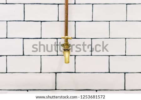 front view with space for text, Retro golden water tap with copper pipes on wall with white tiles