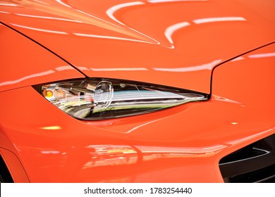 Front View Of Sport Car With Reflection On Bright Orange Paint. Shiny Car After Paint Polish & Ceramic Coat. Car Detailing & Paint Protection Background. Car Wash Concept. Selective Focus.   