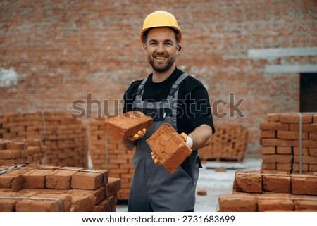 Front view, standing. A builder is working at the construction site at daytime.