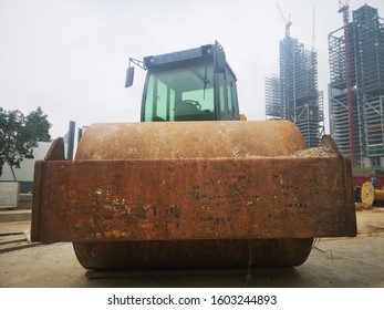 Front View Of Steamroller At Construction Site By Day In Front Of Skyscraper