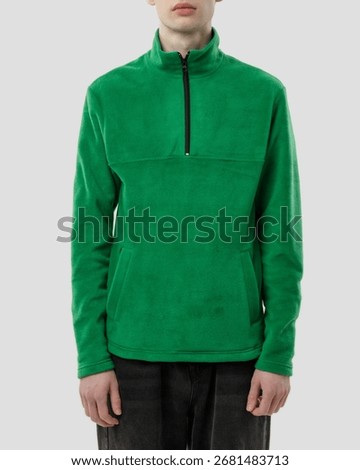 Front view studio shot of a young man wearing a bright green fleece pullover with a half-zip neckline against a white background.
