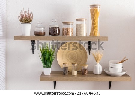 Front view of stylish open kitchen shelves with various eco-jars under bulk products. proper storage and beautiful decor in a modern kitchen