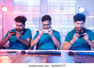 Front View Of Team Of Young Professional Gamers Seriously Playing Of Live Video Game On Mobile Phone At Esports Tournament