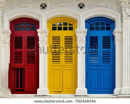 Front view of traditional vintage Singapore shop house or shophouse with antique red, blue and yellow wooden shutters in historic Little India
 