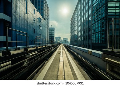 Front view of train in modern city. Straight rail with city buildings background. Transportation by train and railroad concept.
