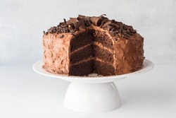 Front View Of A Triple Layered Chocolate Cake With A Large Slice Removed. 