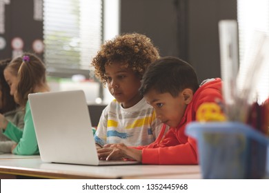 Front View Of Two School Kids Working On One Laptop In Classroom Against School Girl In Background