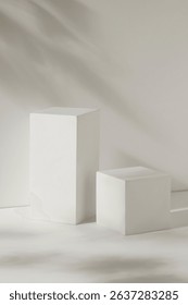 Front view of two white empty podiums displayed on a white background with natural leaves shadow. Blank minimalist empty showcase template